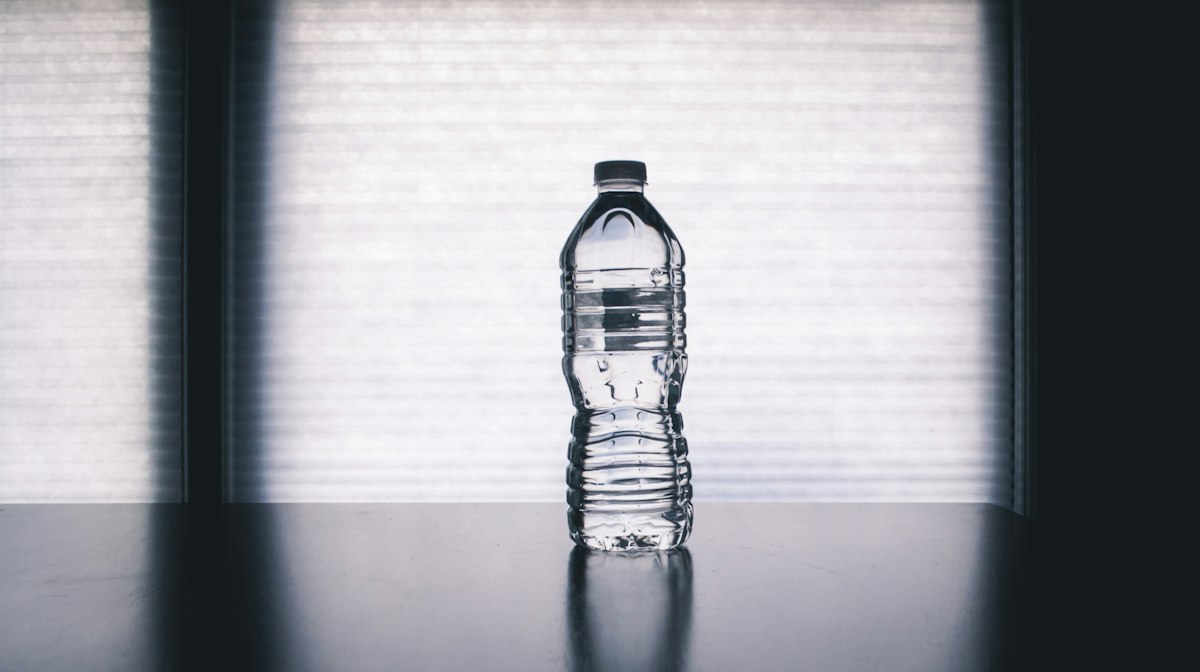Clear glass bottle of electrolyte water with fresh citrus lemon slices showing optimal sports hydration