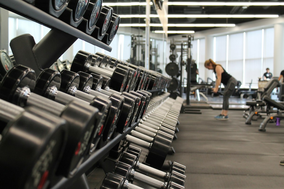 Heavy dumbbell row station in modern fitness facility demonstrating compound athletic training